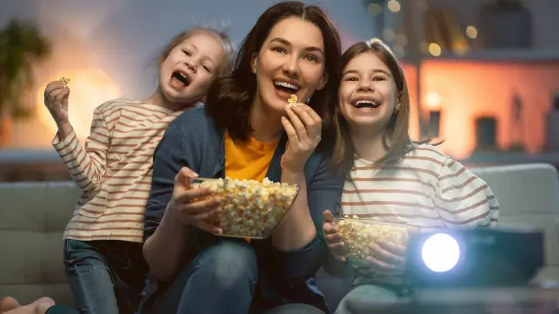 Familia riendo mientras ve una película juntos